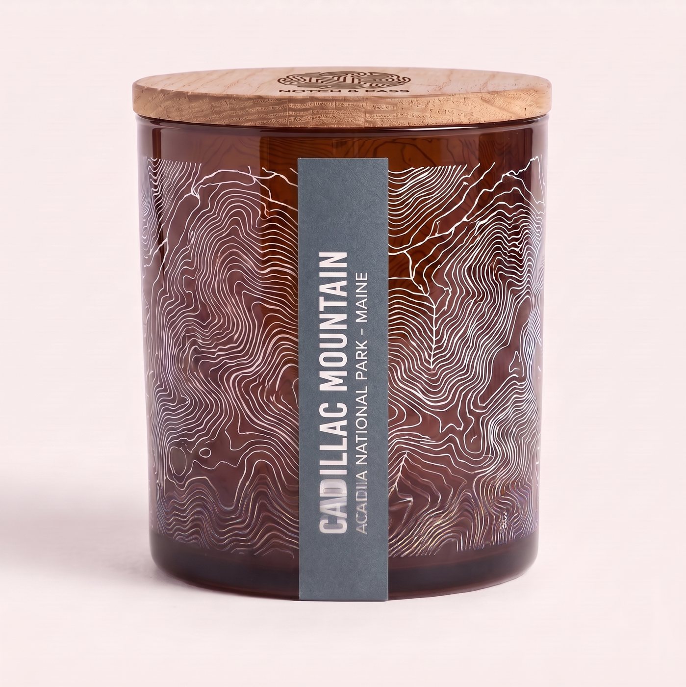 The Cadillac Mountain candle: amber glass, its sheet printed in white, a slate blue estate-paper label, pine lid with the mark