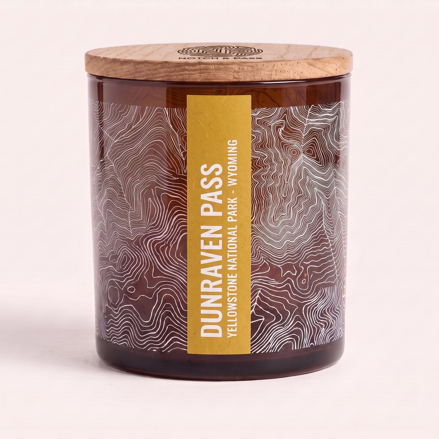 The Dunraven Pass candle: amber glass, its sheet printed in white, a ochre estate-paper label, pine lid with the mark