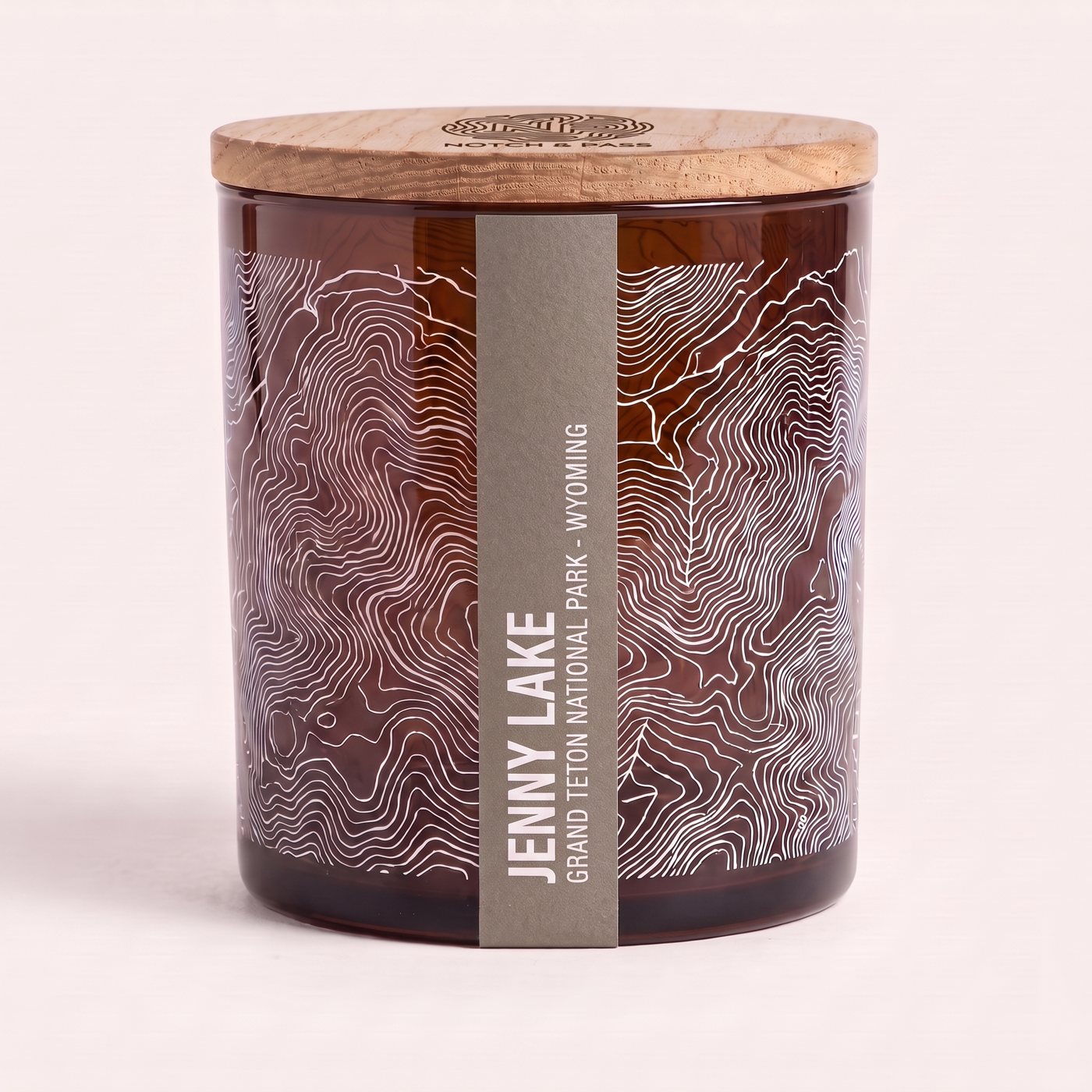 The Jenny Lake candle: amber glass, its sheet printed in white, a stone grey estate-paper label, pine lid with the mark