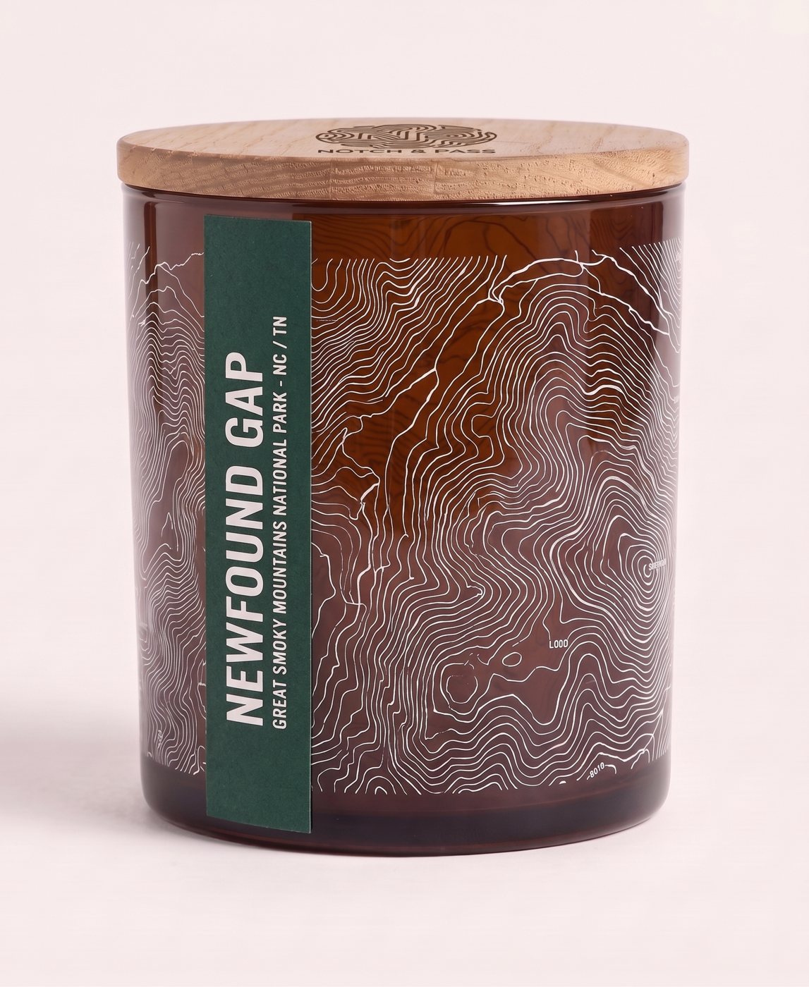 The Newfound Gap candle: amber glass, its sheet printed in white, a spruce green estate-paper label, pine lid with the mark