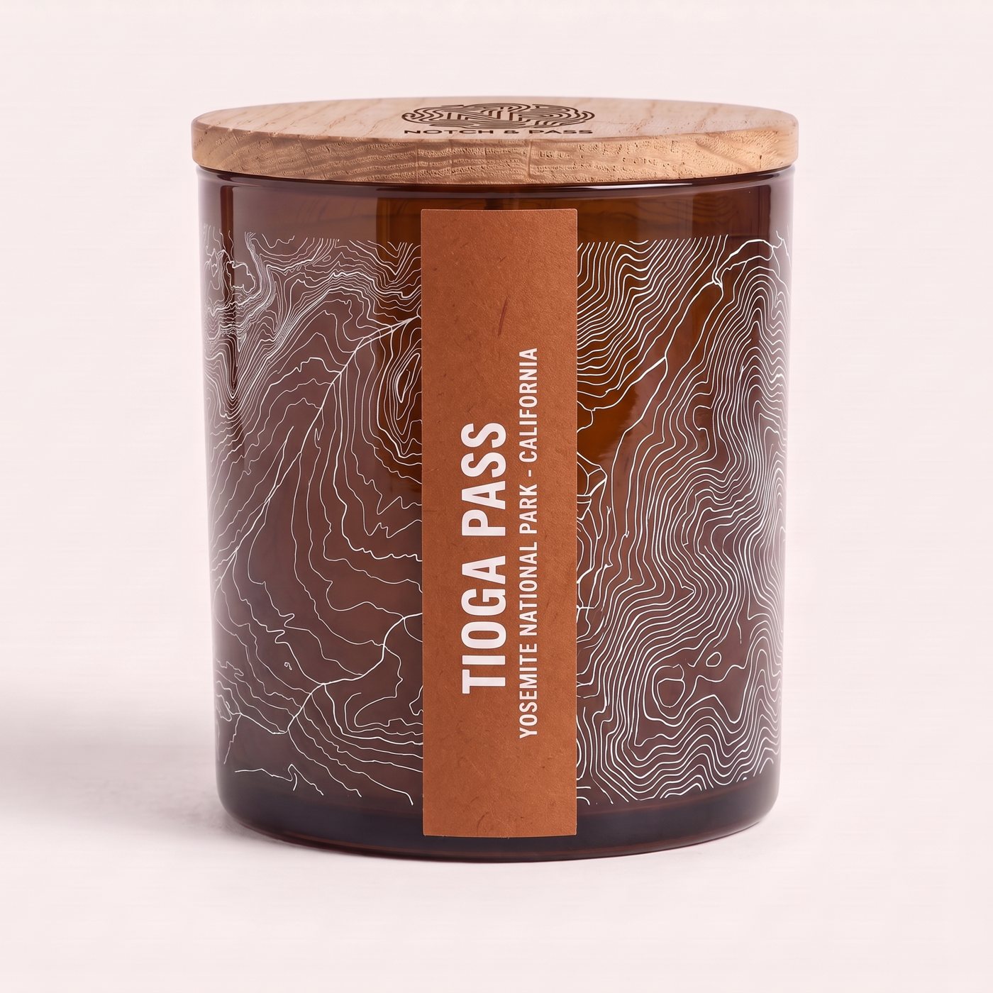 The Tioga Pass candle: amber glass, its sheet printed in white, a burnt sienna estate-paper label, pine lid with the mark