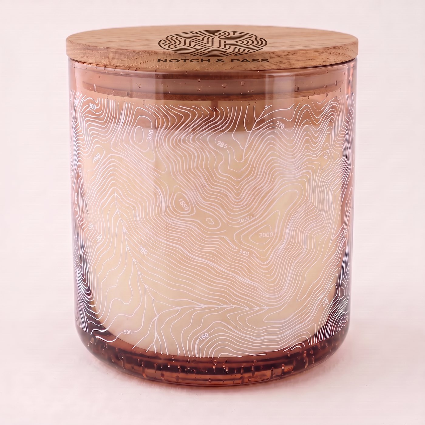 The Juniper & Tonka candle: amber bubble glass, white contour print, pine lid with the mark burnt in