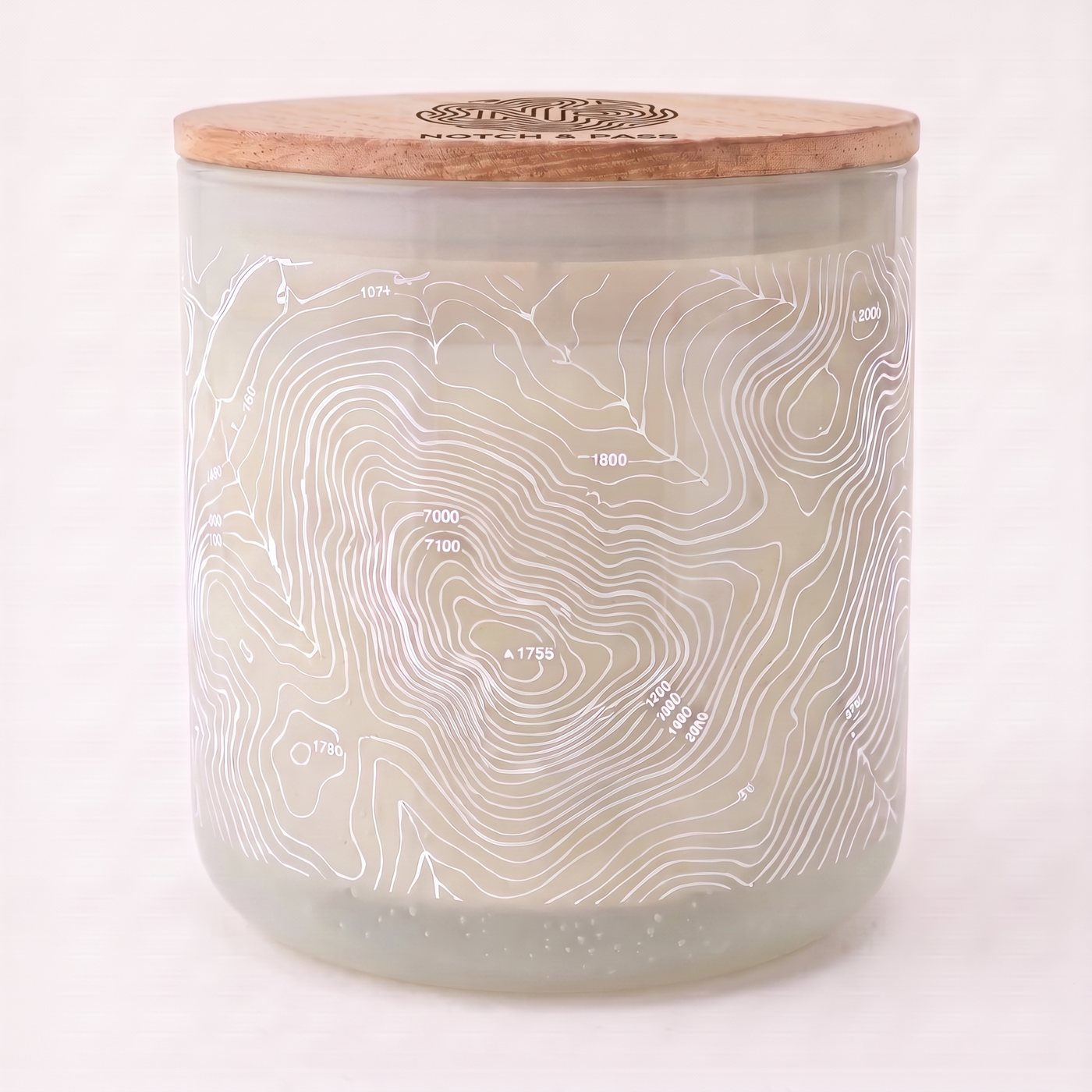 The Sage & Palo Santo candle: opaline cream glass, white contour print, pine lid with the mark burnt in
