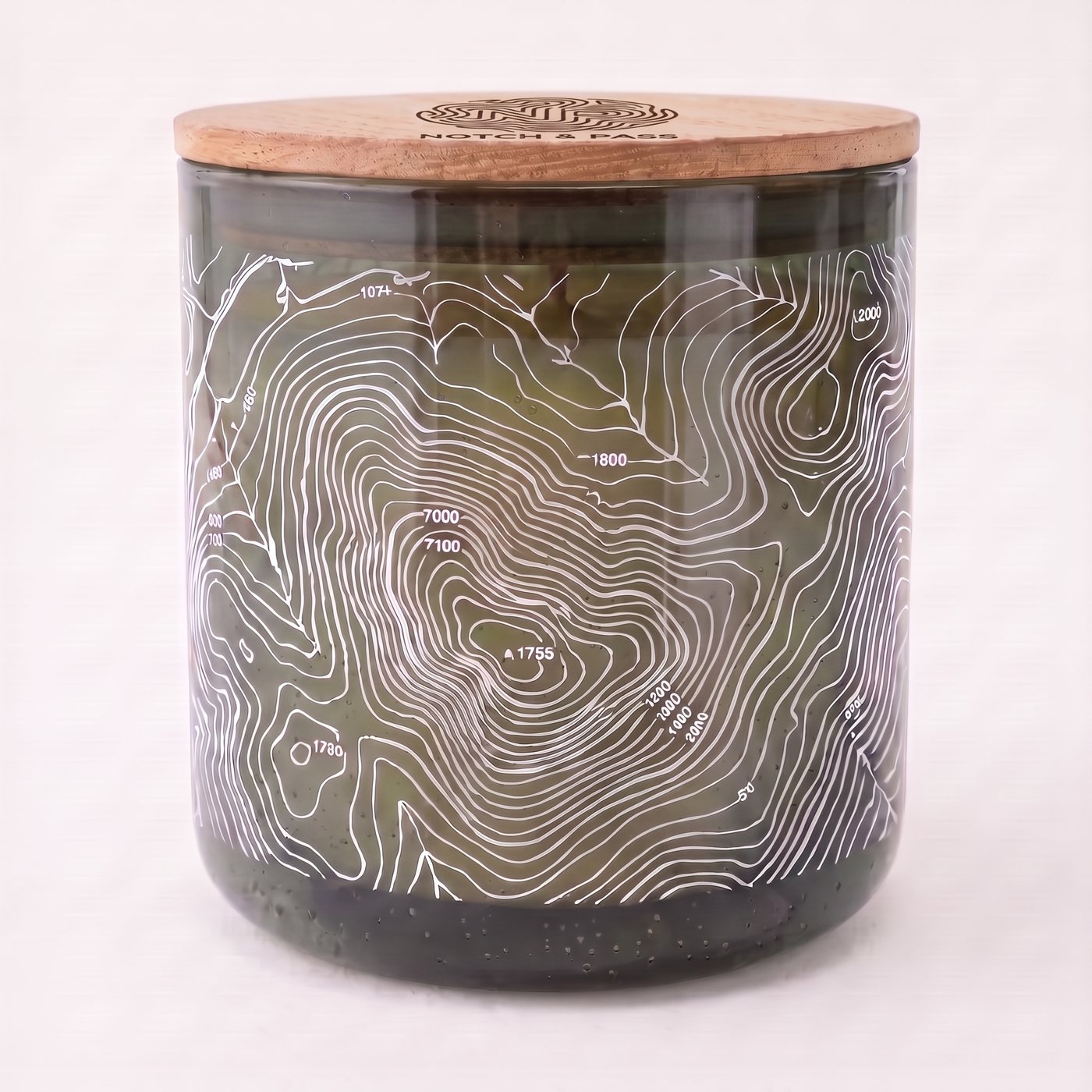 The Woodsmoke & Birch Tar candle: smoked olive glass, white contour print, pine lid with the mark burnt in
